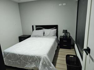 昆卡apartamento de lujo的一间卧室配有白色床单和2个床头柜