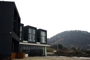 济州市Jeju Claire de lune的一座黑色的建筑,背景是一座山