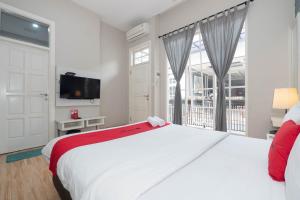 雅加达RedDoorz Premium near RS Pondok Indah La Maison的一间白色卧室,配有一张大床和一台电视