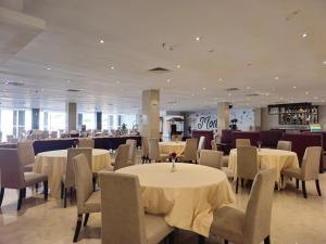 巴淡岛中心Grand Sydney Hotel的一间设有白色桌椅的用餐室