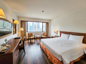 曼谷曼谷华美达迪马阁酒店的配有一张床、一张桌子和一张桌子的酒店客房