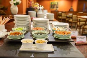 曼谷曼谷华美达迪马阁酒店的自助餐,包括盘子和碗的食品在桌上