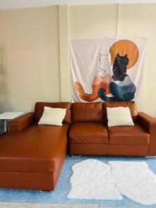 普吉镇Rustic apartment at YaNui beach的一张棕色皮沙发,上面坐着一只黑猫