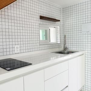 江陵市屋顶月光度假屋的白色瓷砖浴室设有水槽和镜子