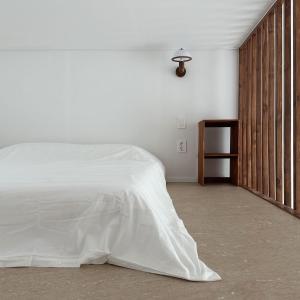 江陵市屋顶月光度假屋的卧室配有白色的床和木墙