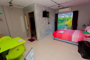 蔻立khaolak big bike&room for rent的一间卧室配有一张床、一把绿色椅子和一扇窗户