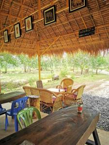 贡布Kampot Camping的草伞下的一张木桌和椅子