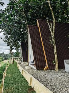 塔巴南PukuPods - Tent & Cabin的一座木外墙建筑,毗邻树木