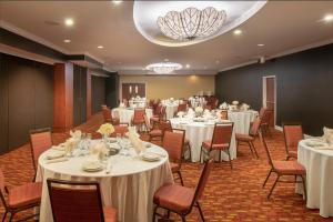 橘园杰克逊维尔橘园万怡酒店的宴会厅配有白色的桌椅和吊灯。