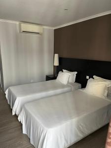 罗安达Casas de Luanda GH-Alvalade的配有白色床单的酒店客房内的两张床