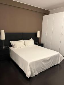 罗安达Casas de Luanda GH-Alvalade的一间卧室配有一张带两盏灯的大型白色床。