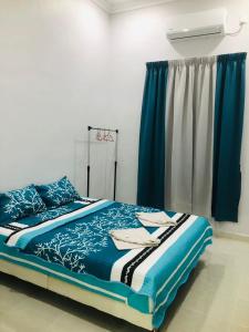 瓜拉丁加奴HOMESTAY CIK PHIA的一间卧室配有一张带蓝色床单的床和一扇窗户。