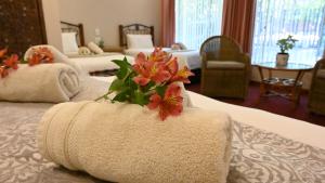 米德尔堡LUXURY FAMILY EN-SUITE ROOM @ 4 STAR GUEST HOUSE的酒店客房,配有两张带毛巾和鲜花的床