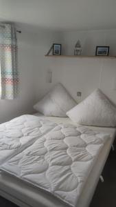 劳雷尔苏格MOBILHEIM HERZ LAUWERSOOG - Chalet Robbengat的一张白色的床,上面有两个枕头