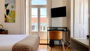 里斯本希尔都特索大巴萨旅馆的一间卧室配有一张床、一张书桌和一个窗户。