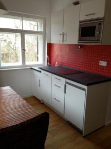 慕尼黑Schöne Wohnung Nahe Engl. Garten的厨房配有白色橱柜和红色瓷砖墙