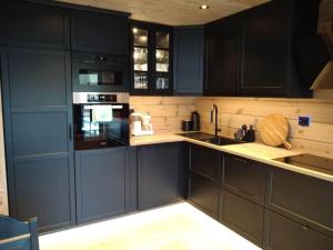 史特林Ny og moderne hytte i Stryn的厨房配有深蓝色橱柜和水槽