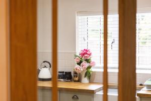 普里茅斯Romantic Cottage的厨房里的柜台上一束粉红色花