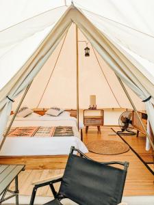 塔巴南PukuPods - Tent & Cabin的一个带一张床和椅子的帐篷