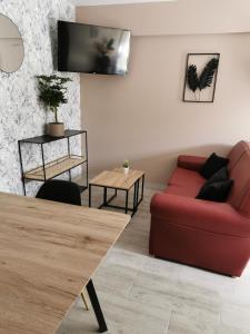 Longues-sur-MerLa chaumière的客厅配有红色的沙发和桌子