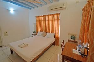蓬蒂切里Villa Waves的一间卧室配有一张床、一张书桌和一个窗户。
