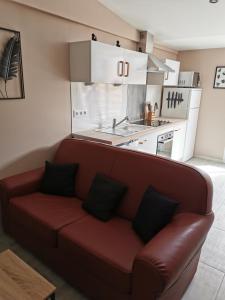 Longues-sur-MerLa chaumière的客厅设有红色沙发,位于厨房内