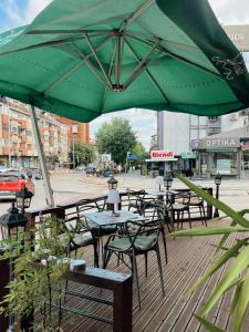 普里什蒂纳Hotel LaCorte Prishtina的一组绿伞下的桌椅