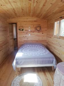 弗维沃Roulotte en bois的小木屋内一间卧室,配有一张床