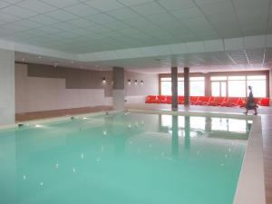 圣福瓦-塔朗泰斯Apartment close to ski lift in Sainte Foy的一个带红色椅子的房间,游泳池里是蓝色的海水