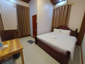 万荣Inthavong Hotel/Guest House的一间带床和木桌的小卧室