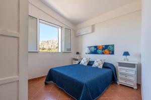 圣维托罗卡波Casa Lia e Nino a San Vito Lo Capo的一间卧室设有蓝色的床和窗户。