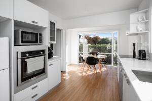 基督城Spacious Quality Apartment, Convenient Location的厨房配有白色橱柜和桌椅