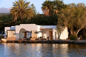 阿基欧斯尼古拉斯Minos Beach Art Hotel, a Member of Design Hotels的水边的房子,配有椅子和遮阳伞