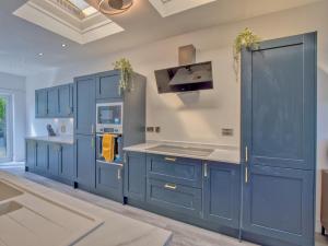 西基尔布赖德Seamill Cottage的蓝色的厨房,配有白色的柜台和蓝色的橱柜