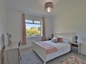 西基尔布赖德Seamill Cottage的一间卧室配有一张床、一个窗口和一张书桌