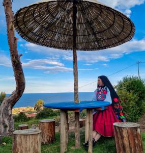 奥科苏尤Inca lodge - Amantani的坐在桌子上,在伞下的一个女人