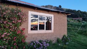 奥科苏尤Inca lodge - Amantani的窗户上反射着日落的房子