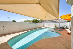 拉斯维加斯Sunny Las Vegas Studio with Shared Pool and Backyard!的一个带遮阳伞和桌椅的游泳池