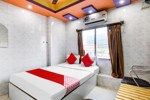 GauripurOYO Flagship The Rest的客房配有带红色枕头的床和窗户。