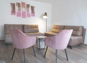 Hegyköz Vendégház的客厅配有2把粉红色的椅子和沙发