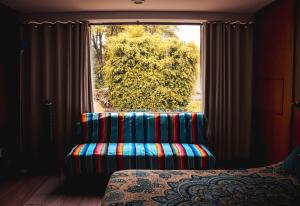 墨西哥城Suites Cuija Coyoacan的窗户前带椅子的房间