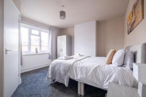 BirstallStunning Home Ideal for Business - Free Parking的一间卧室配有一张带白色床单的床和一扇窗户。