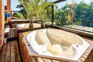 弗洛里亚诺波利斯Resort pé na areia - Suítes JBVTOP的木制甲板上的浴缸,设有窗户