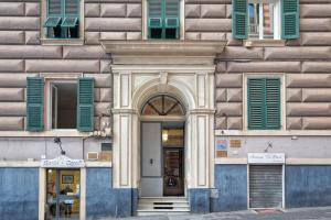 热那亚Le Due Piazze的通往带绿色百叶窗的建筑的入口