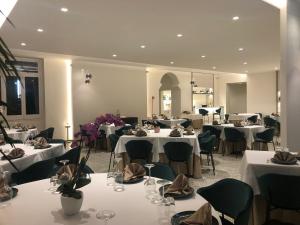 塞尔瓦迪法萨诺Hotel La Silvana的一间设有白色桌椅的餐厅,并鲜花盛开