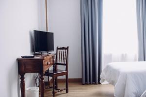 Viveda雀利酒店的一间卧室配有一张桌子、一台电视和一张床