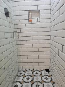 别霍港Mecca的白色瓷砖淋浴间铺有黑白色瓷砖地板。
