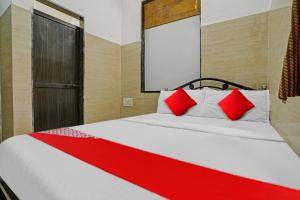 孟买OYO Flagship Raj Hotel Near Juhu Beach的一间卧室配有一张带红色枕头的大床