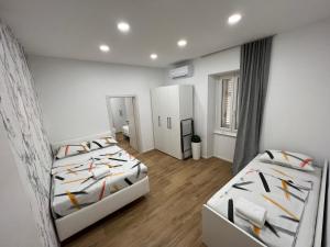 皮兰Grand Apartment Piran的配有白色墙壁和木地板的客房内的两张床