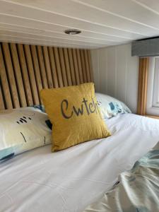 LlanelltydCwtch Cader Shepherds Hut的一张带黄色枕头的床,上面有“外延”字样